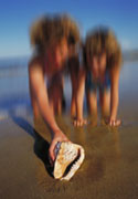 PHOTO : Deux enfants trouvant un strombe sur la plage.